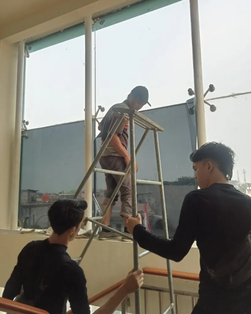 Tim memasang kaca film pada kaca besar