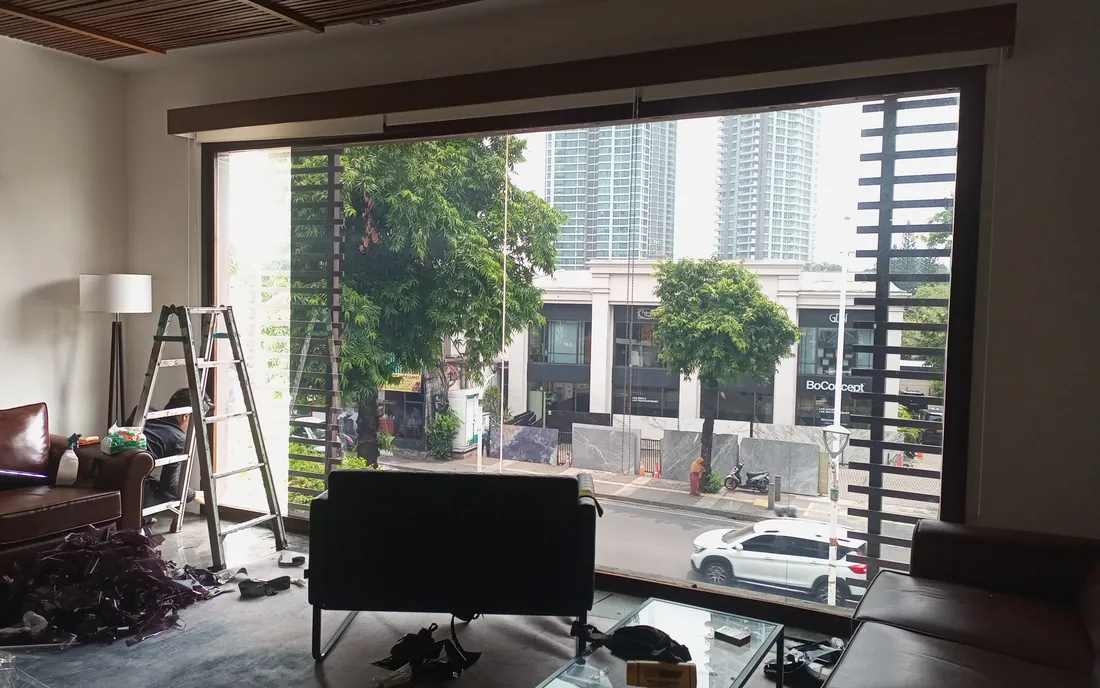 Ruang tamu dengan jendela kaca besar saat proses pemasangan kaca film